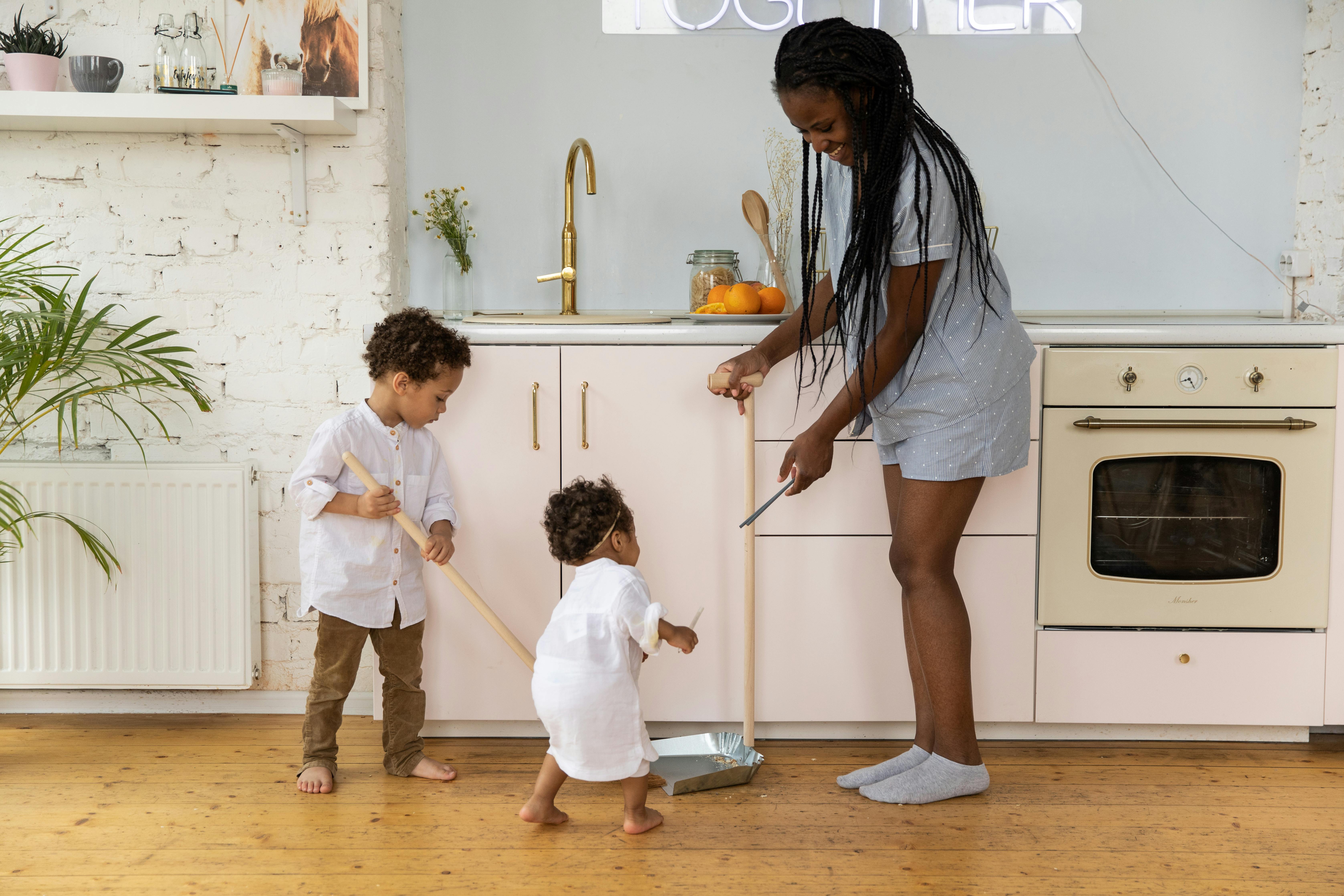 Fostering Communication Through Everyday Activities A mother and her two children cleaning together in a bright, modern kitchen.