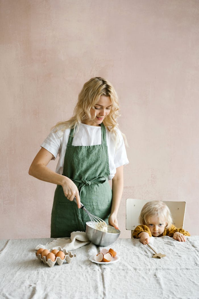 Raising Bilingual Communicators A mother and her young daughter baking together in the kitchen, creating a joyful bonding moment.
