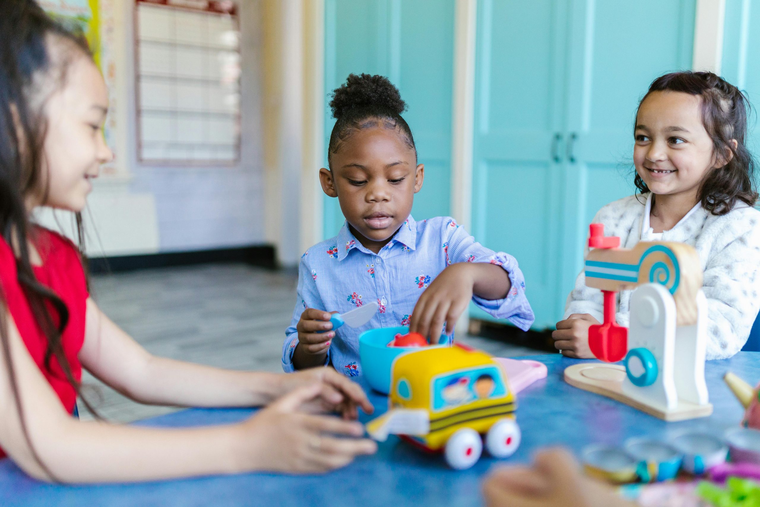 Young children playing and learning with toys in a bright classroom setting.