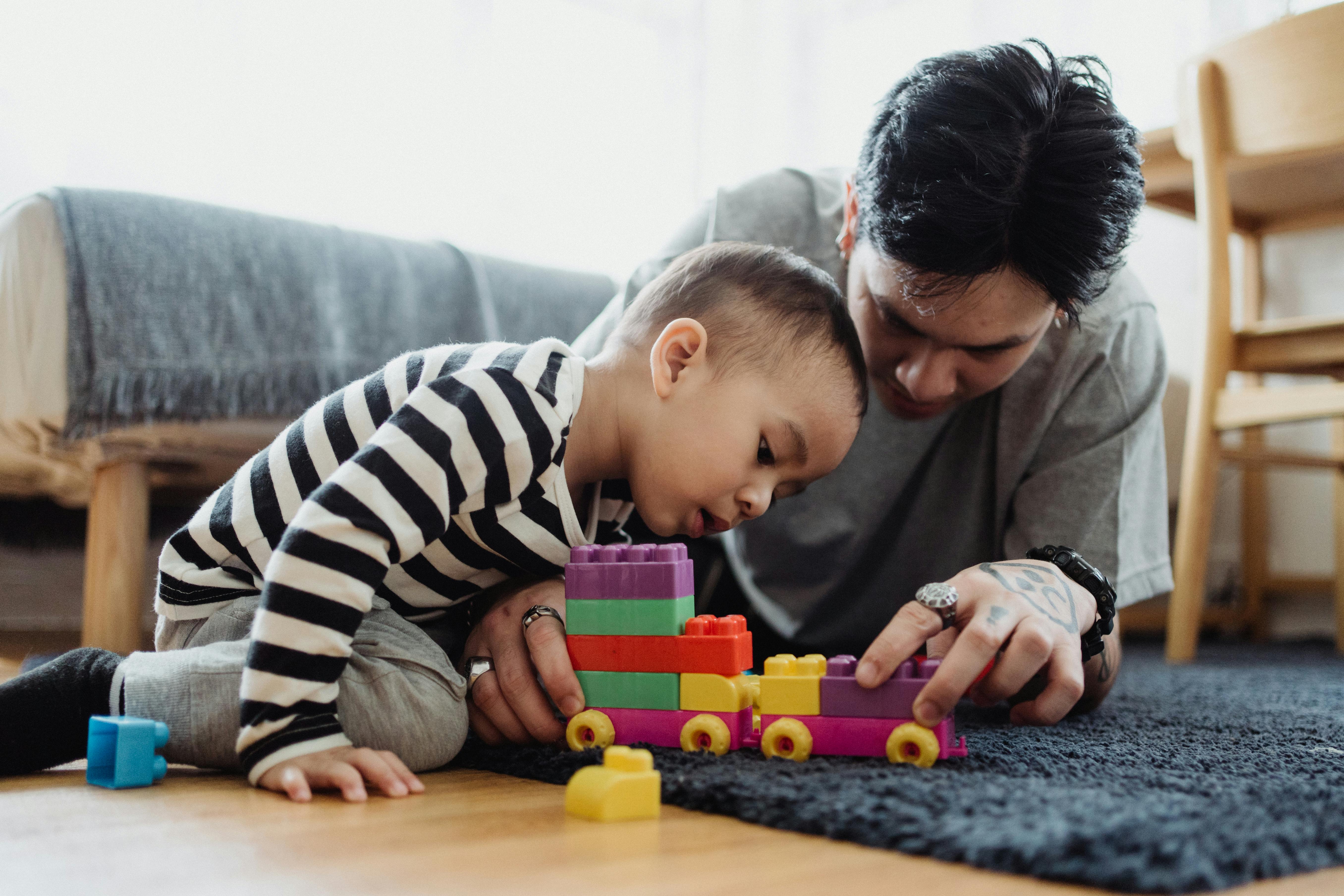 Playtime Adventures: How Playing with Children Boosts Vocabulary and Language Skills A father and son bonding while playing with colorful blocks indoors.