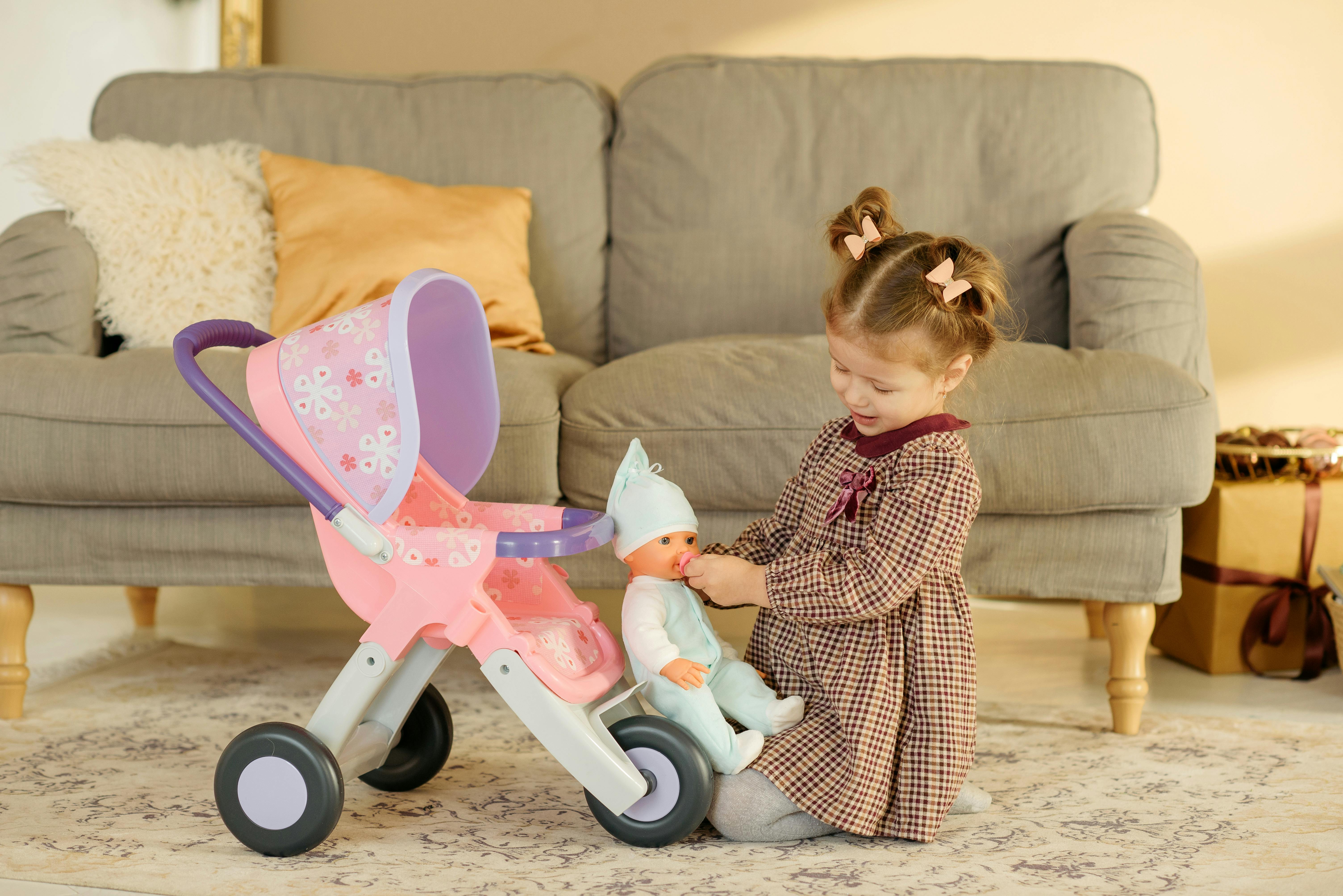 Adorable child playing with a doll and stroller in a cozy living room setting.