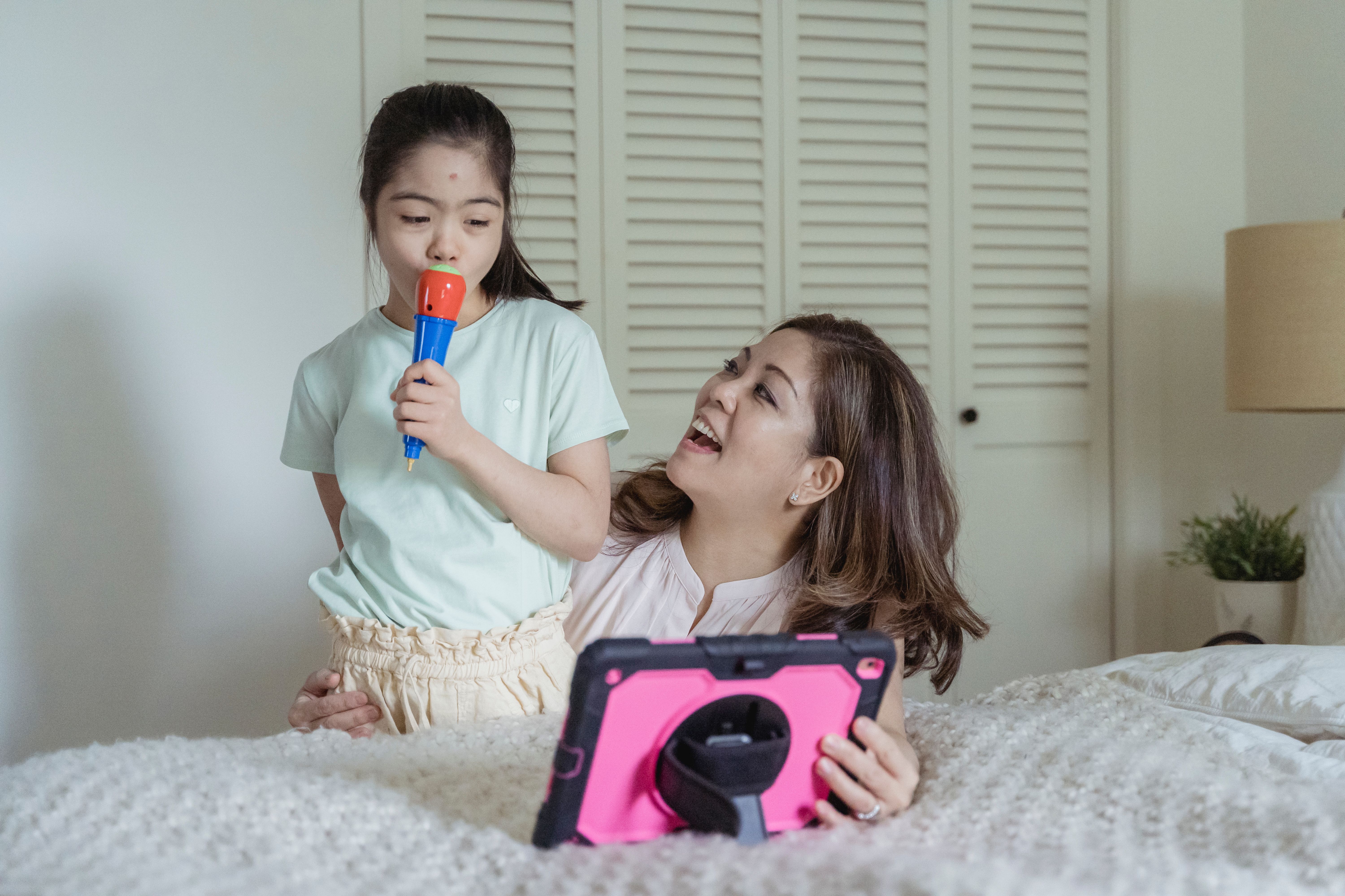 A joyful mother and daughter enjoying a karaoke session with a tablet at home.